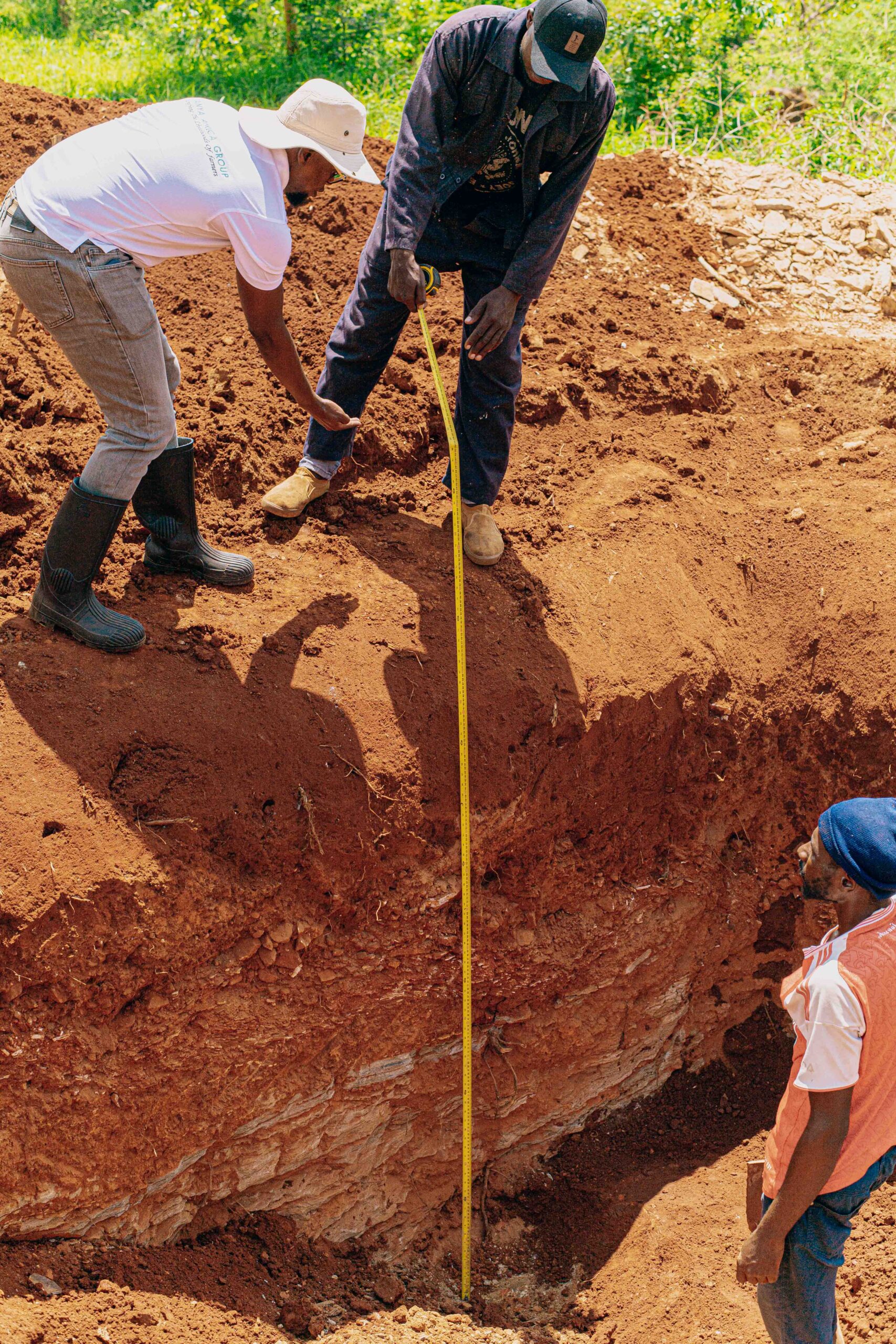 IAG co-founder as well as some local young men take the measurements of a water pan being constructed.